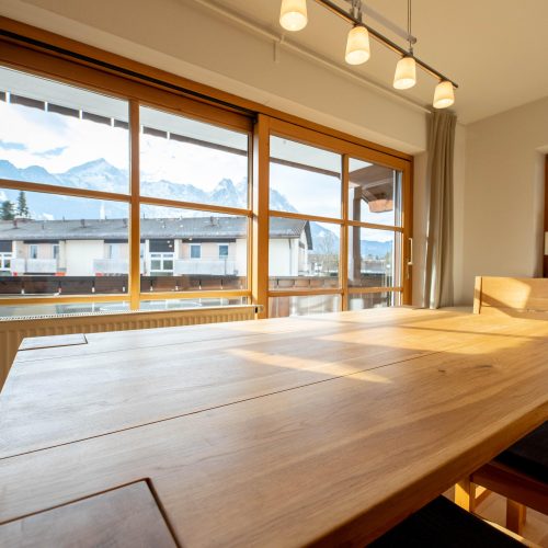 Holztisch mit Deckenlampe und Stühlen in Ferienwohnung in Garmisch-Partenkirchen