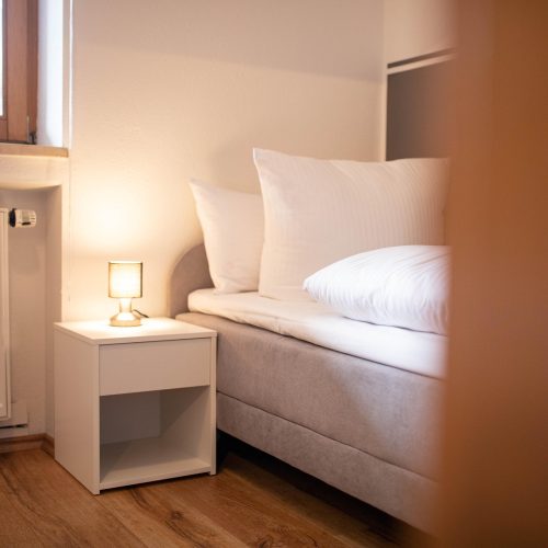 Einzelbett mit kleinem Nachtschrank und kleinem Licht in Ferienwohnung in Garmisch-Partenkirchen
