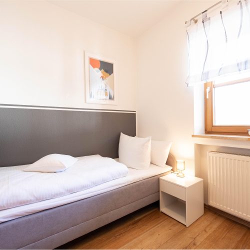 Einzelbett mit kleinem Nachtschrank in Ferienwohnung in Garmisch-Partenkirchen