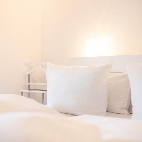 Weißes Bett mit Kissen in Ferienwohnung in Garmisch-Partenkirchen