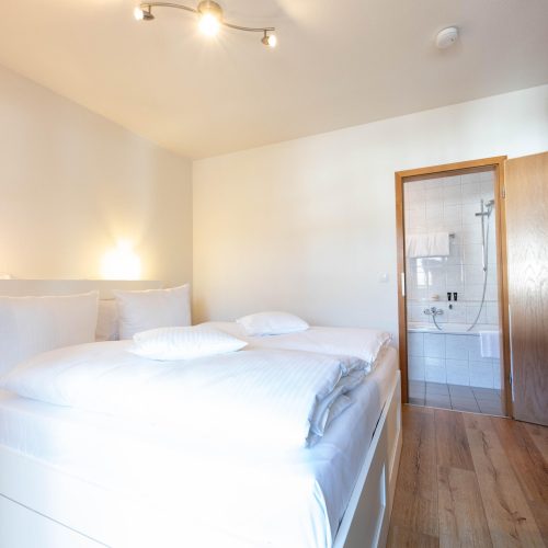 Schlafzimmer mit einem großen weißen Doppel-Bett in Ferienwohnung in Garmisch-Partenkirchen