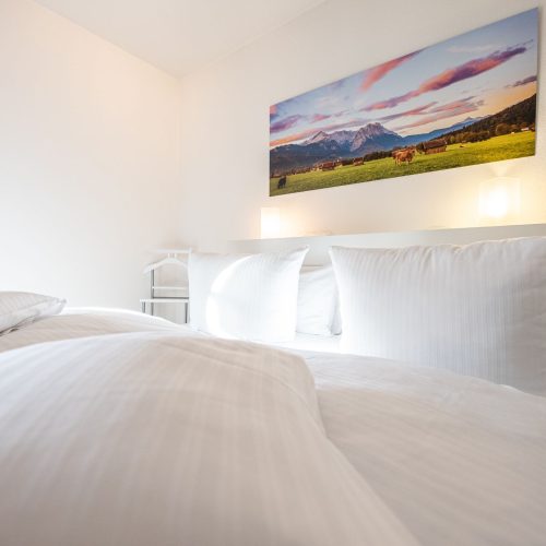 Weiches Bett mit Bergbild in Ferienwohnung in Garmisch-Partenkirchen