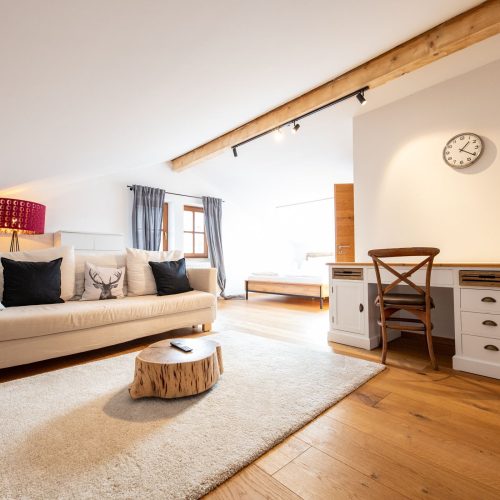 Wohnbereich mit einem creme farbenen Sofa und einem kleinen Schreibtisch in Ferienwohnung in Garmisch-Partenkirchen