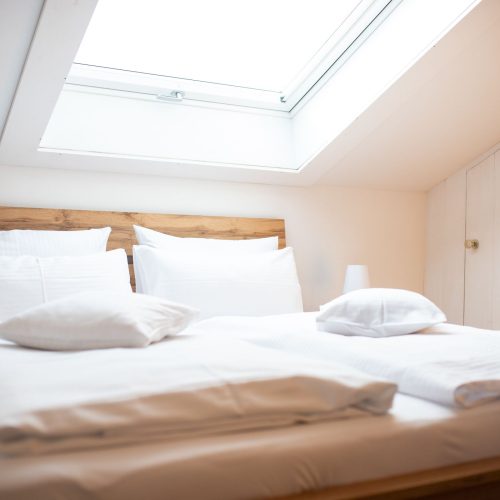 Doppelbett neben einer weißen kleinen Tür in Ferienwohnung in Garmisch-Partenkirchen