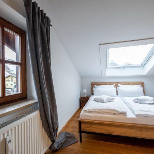 Schlafzimmer mit einem Doppelbett und zwei Fenstern in Ferienwohnung in Garmisch-Partenkirchen