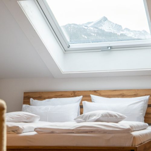 Schlafzimmer mit einem Holz-Doppelbett mit Dachfenster in Ferienwohnung in Garmisch-Partenkirchen