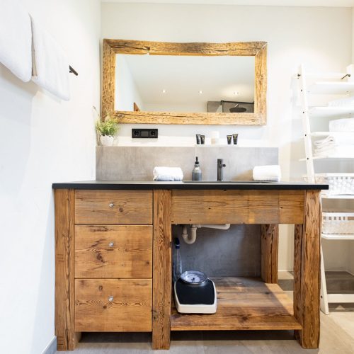 Badezimmer mit Sicht auf einen Spiegel und den braun-schwarze Waschbecken-Bereich in Ferienwohnung in Garmisch-Partenkirchen