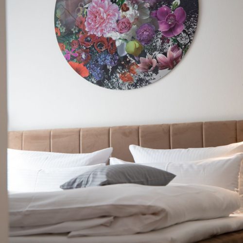 Blick auf rundes Blumenbild über Bett in Ferienwohnung in Garmisch-Partenkirchen