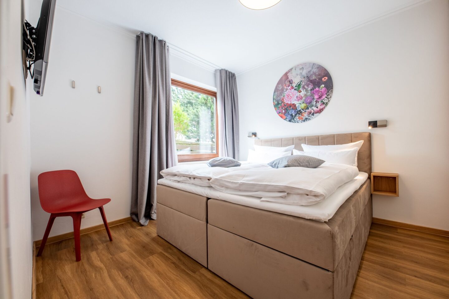 Boxspringbett mit rotem Stuhl in Ferienwohnung in Garmisch-Patenkirchen