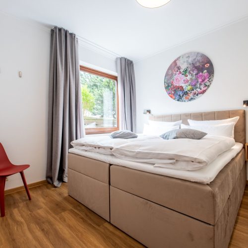 Boxspringbett mit rotem Stuhl in Ferienwohnung in Garmisch-Patenkirchen