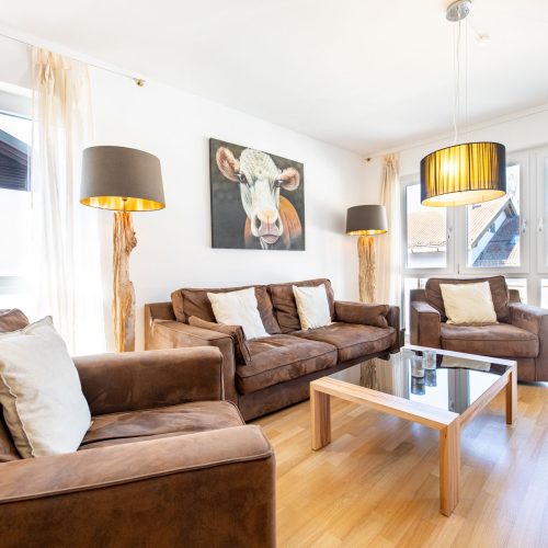 Wohnbereich mit braunen Möbeln und großen Fenstern in Ferienwohnung in Garmisch-Patenkirchen