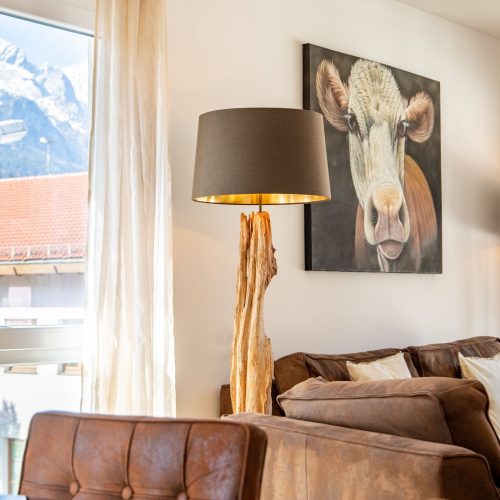 Sofa zwischen zwei Lampen mit Holzstamm in Ferienwohnung in Garmisch-Patenkirchen