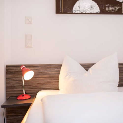 Bett mit Holzrückwand und weißen Kissen in Ferienwohnung in Garmisch-Patenkirchen