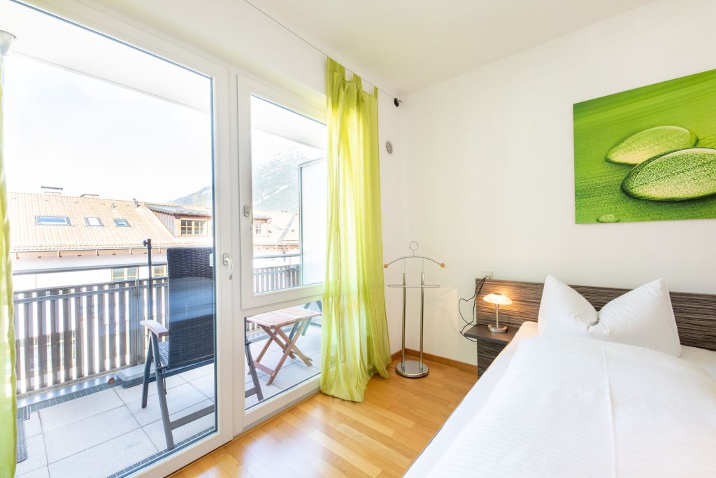 Bett mit grünem Bild und hellgrünen Gardinen