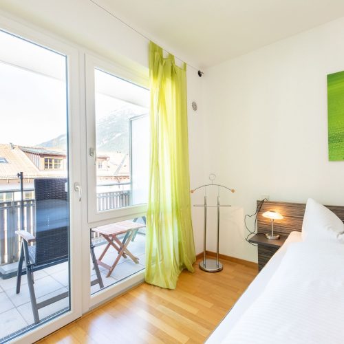 Bett mit grünem Bild und hellgrünen Gardinen in Ferienwohnung in Garmisch-Patenkirchen