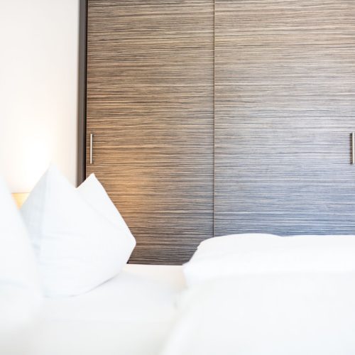 Weiches Bett mit weichen Kissen und großem Holzschrank in Ferienwohnung in Garmisch-Patenkirchen