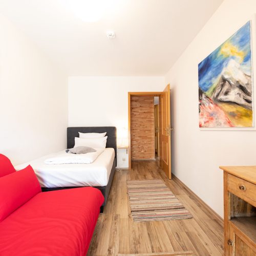 Schlafzimmer mit rotem Sofa in Ferienwohnung in Garmisch-Partenkirchen
